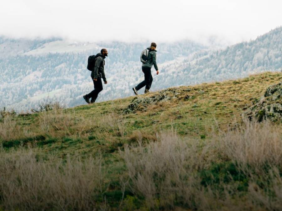 Two people in autumnal hiking gear are crossing a mountain
