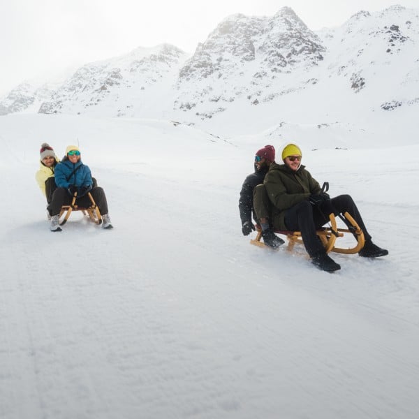 Three people sitting on a sledge in the snow